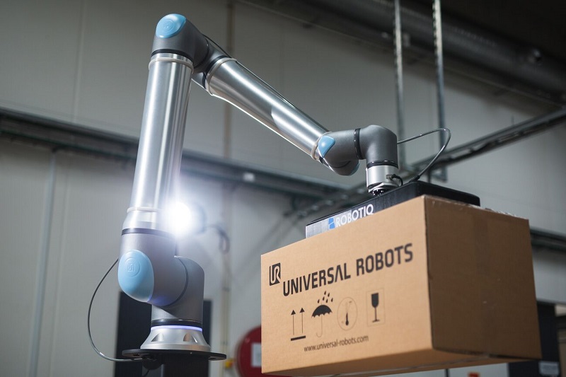Un robot con gripper sujetando una caja en un proceso logistico